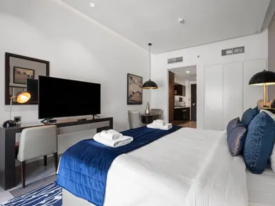 a bedroom with a bed with a desk and a tv at Sunlit Studio Haven Luxury Living in Majestine in Dubai