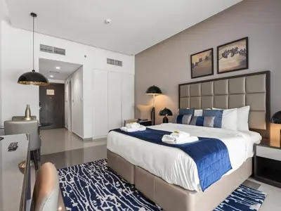 a bedroom with a large bed and a blue rug at Sunlit Studio Haven Luxury Living in Majestine in Dubai
