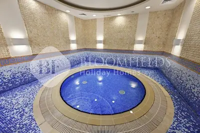 a swimming pool in a building with a large blue tub at Bloomfields Iconic 2BR Elite Residence Marina in Dubai