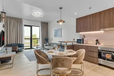 a kitchen and living room with a table and chairs at Port De La Mer by Hosteeva in Dubai