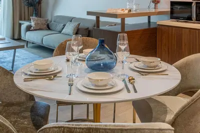 a table with plates and glasses and a blue vase at Port De La Mer by Hosteeva in Dubai