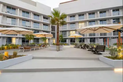 a courtyard with chairs and umbrellas in front of a building at Vogue JVC Luma22 near Circle Mall, Studio Apartment with Balcony and Vibrant Community View, Access to all Amenities in Dubai