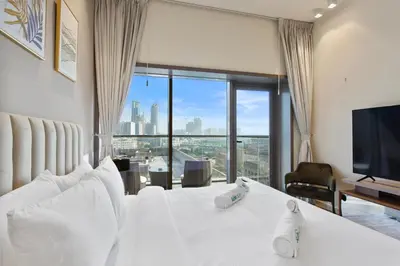 a bedroom with a white bed and a large window at Upscale Studio in Park View JVC in Dubai