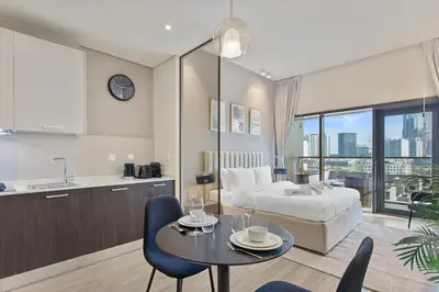 a kitchen and a living room with a bed and a table at Upscale Studio in Park View JVC in Dubai