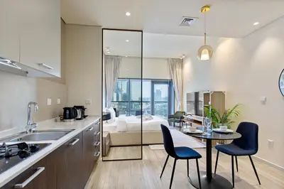 a kitchen with a table and chairs and a bedroom at Upscale Studio in Park View JVC in Dubai