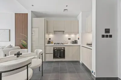 a kitchen with white cabinets and a table and chairs at Luxury 1BR Apartment Near Burj Khalifa Skyline Pool View in Dubai