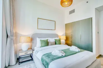a bedroom with a large bed with green pillows at PVH - Serene Central 2BR - Creek Horizon in Dubai