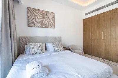a bedroom with a large white bed with blue pillows at Modern Studio Apartment with Outdoor views I Azizi 67 in Dubai