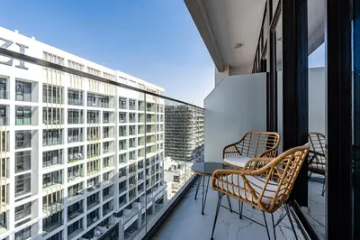 a balcony with two chairs and a table and a building at Modern Studio Apartment with Outdoor views I Azizi 67 in Dubai