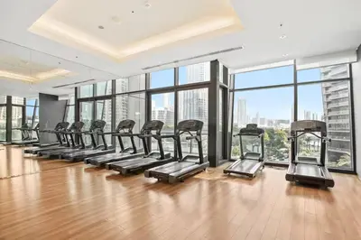 a gym with a row of treadmills and large windows at Connection to Dubai Mall, 2 King Beds, with Pool, Gym, Tennis Court in Dubai
