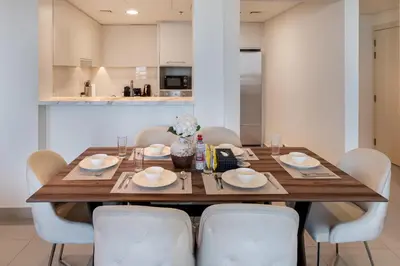 a dining room table with white chairs around it at Connection to Dubai Mall, 2 King Beds, with Pool, Gym, Tennis Court in Dubai