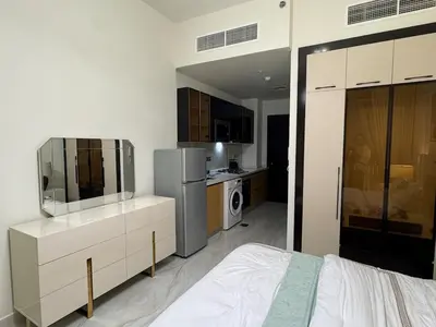a bedroom with a bed and a tv and a kitchen at Smart Studio in Gemz in Dubai