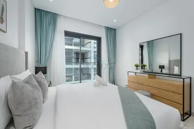 a white bedroom with a large bed and a mirror at Prime location near the park, just minutes from the metro, with easy access to all of Downtown Dubai attractions, Viridian, Al Wasl by Deluxe Holiday Homes in Dubai