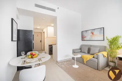 a living room with a couch and a table at Vogue JVC Luma22 near Circle Mall, Studio Apartment with Balcony and Vibrant Community View, Access to all Amenities in Dubai