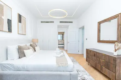 a white bedroom with a large bed and a table at PVH - Coastal 2BR with Beach Access - Atlantic Oceana in Dubai