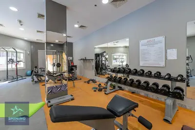 a gym with a lot of equipment and a mirror at Peaceful 1BR JVC Near Circle Mall Pool Gym in Dubai
