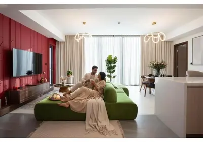 a man and woman sitting on a green couch in a living room at Luxury 3BR Skyline Apartment - Sobha The Crest Dubai in Dubai