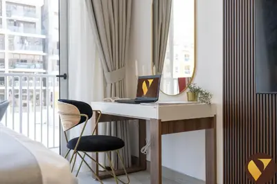 a bedroom with a desk with a laptop and a mirror at Vogue JVC Luma22 near Circle Mall, Studio Apartment with Balcony and Vibrant Community View, Access to all Amenities in Dubai