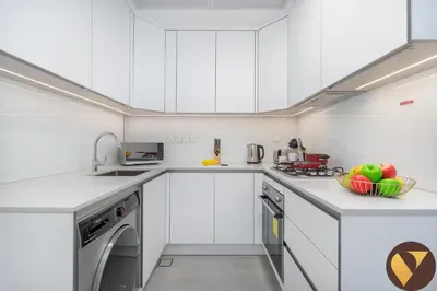 a kitchen with white cabinets and a dishwasher at Vogue JVC Luma22 near Circle Mall, Studio Apartment with Balcony and Vibrant Community View, Access to all Amenities in Dubai