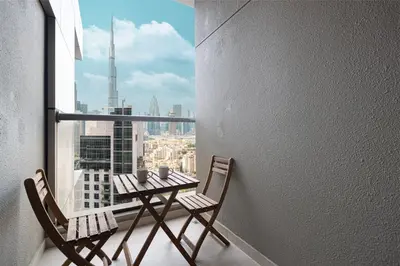a table and chairs on a balcony with a view of a city at Enjoy 8-Day NYE Spectacles with Burj Khalifa View in Dubai