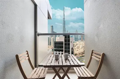 a table and chairs on a balcony with a view of a city at Enjoy 8-Day NYE Spectacles with Burj Khalifa View in Dubai