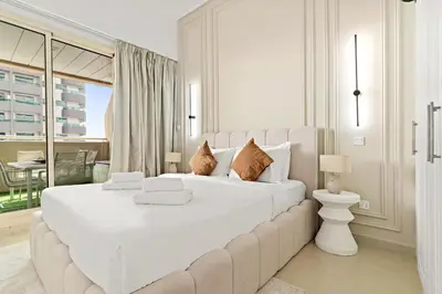 a white bedroom with a large white bed and a balcony at VayK - Vibrant and Great 1BR in the Marina in Dubai