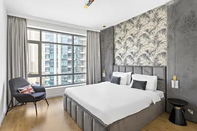a bedroom with a large bed and a chair at VayK - Exquisite 2BR with Panoramic Marina View in Dubai