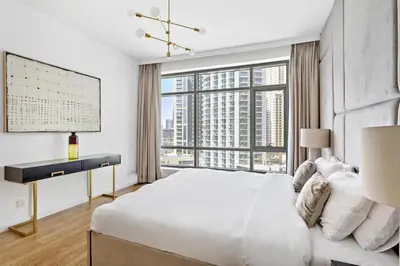 a white bedroom with a large bed and a window at VayK - Exquisite 2BR with Panoramic Marina View in Dubai
