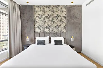 a bedroom with a large white bed and a wall at VayK - Exquisite 2BR with Panoramic Marina View in Dubai