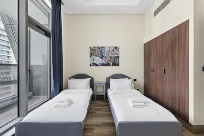 two beds in a room with a window at Vayk - Spacious and Vibrant 2BR Apartment in Business Bay in Dubai