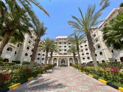 a large building with palm trees and a walkway at VayK - Stylish 1BR in Palm Jumeirah with Secluded Beach Access in Dubai
