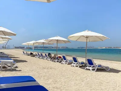a row of chairs and umbrellas on a beach at VayK - Stylish 1BR in Palm Jumeirah with Secluded Beach Access in Dubai