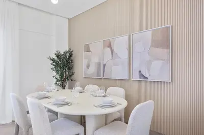 a white dining room with a white table and chairs at Elevated 2 Bedroom with Khalifa view in Peninsula in Dubai