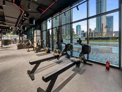 a gym with rows of treadmills in front of windows at Elevated 2 Bedroom with Khalifa view in Peninsula in Dubai