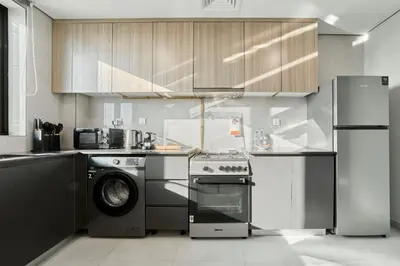 a kitchen with a stove and a washer and dryer at Chic 1BR Getaway in Tulip Oasis 9 Majan in Dubai