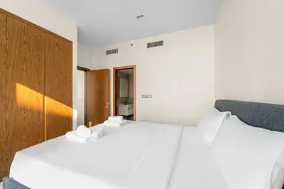 two beds in a bedroom with white sheets at VayK - Chic Marina-Front 1BR in a Luxurious Location in Dubai