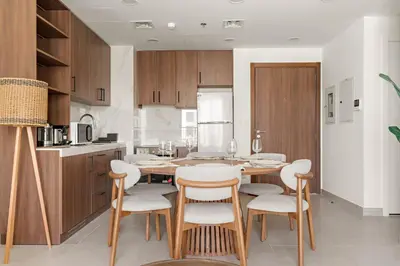 a kitchen with a wooden table and chairs at VayK - Chic 2BR in Town Square with Pool View in Dubai