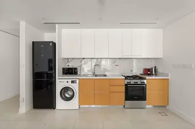 a kitchen with white cabinets and a washer and dryer at VayK - Feel the Festive Vibe in Cozy 1BR with Beach Access in Dubai