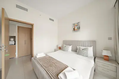 a white bedroom with a large bed and a door at VayK - Iconic 1BR in Downtown in Dubai