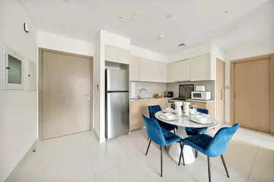 a kitchen and dining room with a table and blue chairs at VayK - Iconic 1BR in Downtown in Dubai