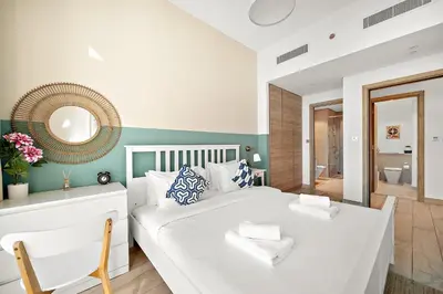 a bedroom with a white bed and a mirror at VayK - Bright and Stylish 1BR in Marina in Dubai