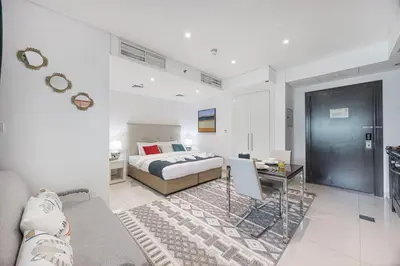 a bedroom with a bed and a living room at Stylish Stay at DAMAC Maison Cour Jardin Canalview in Dubai