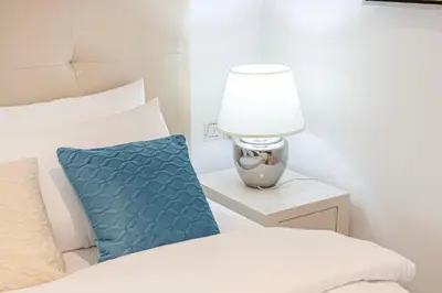 a bedroom with a bed with a blue pillow and a lamp at Stylish Stay at DAMAC Maison Cour Jardin Canalview in Dubai