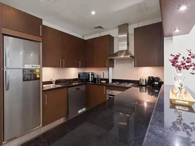 a kitchen with wooden cabinets and a stainless steel refrigerator at Dreamy Haven Studio in West Wharf in Dubai