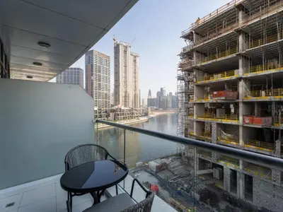 a balcony with two chairs and a view of a river at Dreamy Haven Studio in West Wharf in Dubai