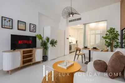 a living room with a couch and a tv and a table at LUX The Palm Sea View Studio in Dubai