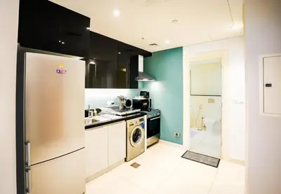 a kitchen with a refrigerator and a washing machine at Escape24 Cozy Studio at Capital Bay near Burj Khalifa in Dubai