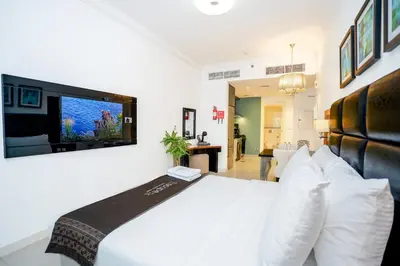 a bedroom with a white bed with a television on the wall at Escape24 Cozy Studio at Capital Bay near Burj Khalifa in Dubai