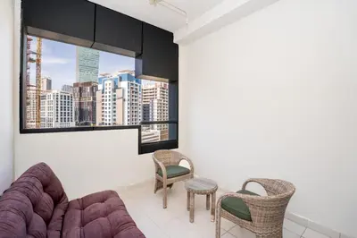a living room with a couch and chairs and a window at Escape24 Cozy Studio at Capital Bay near Burj Khalifa in Dubai