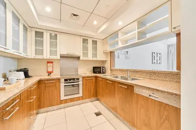 a kitchen with wooden cabinets and a large window at Golden Homes Aqua Bay 1BR-BLVD CENTRAL Downtown Dubai mall in Dubai